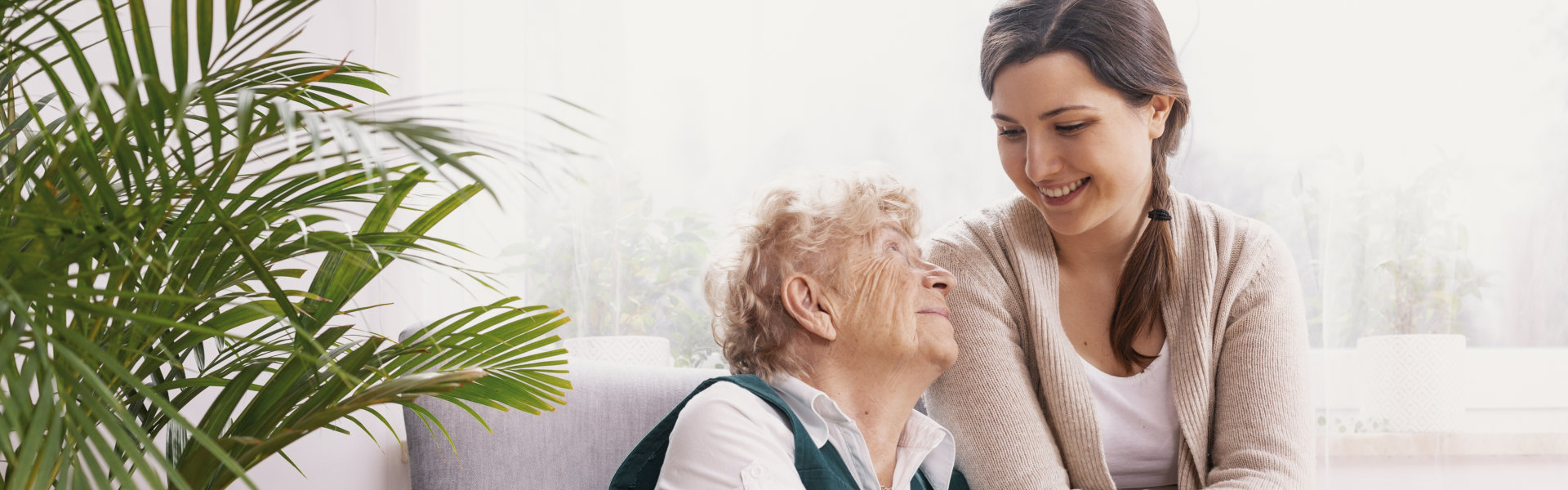 Senior lady sitting in armchair at nursing home, supporting nurse behind her