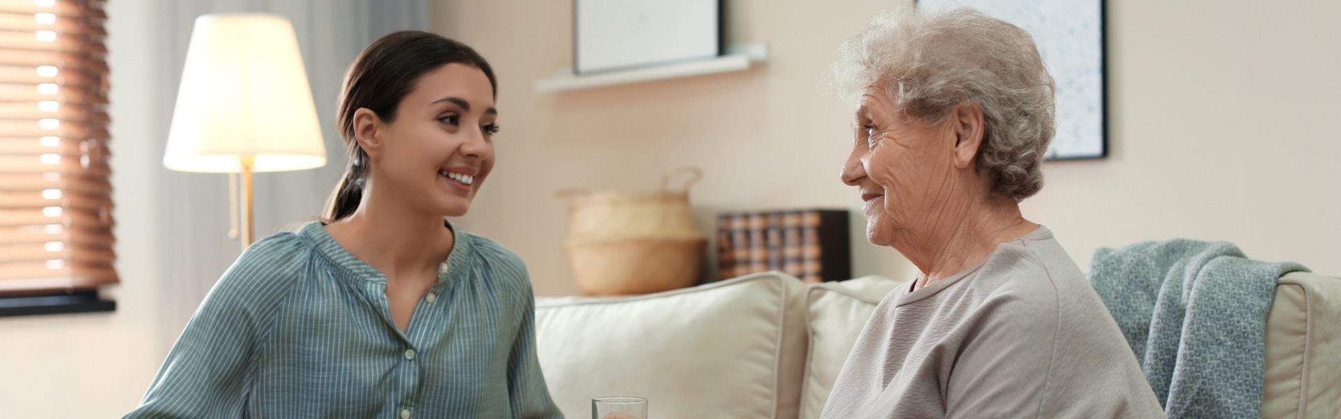 Young women serving dinner for elderly women in living room